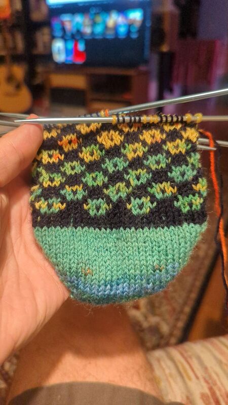 Start of the foot for the second pair of Tour socks, a rainbow Fair Isle motif on a navy background.