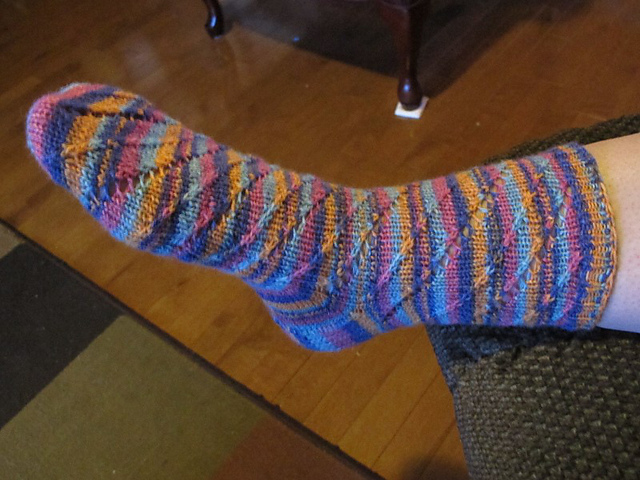 Photo of one of the socks being worn, which opens up the pattern and shows it off.
